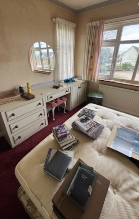 Bedroom with fitted dressing table before HFC clearance — full of belongings